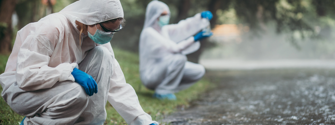 Two scientists in protective suits taking water samples from the river.