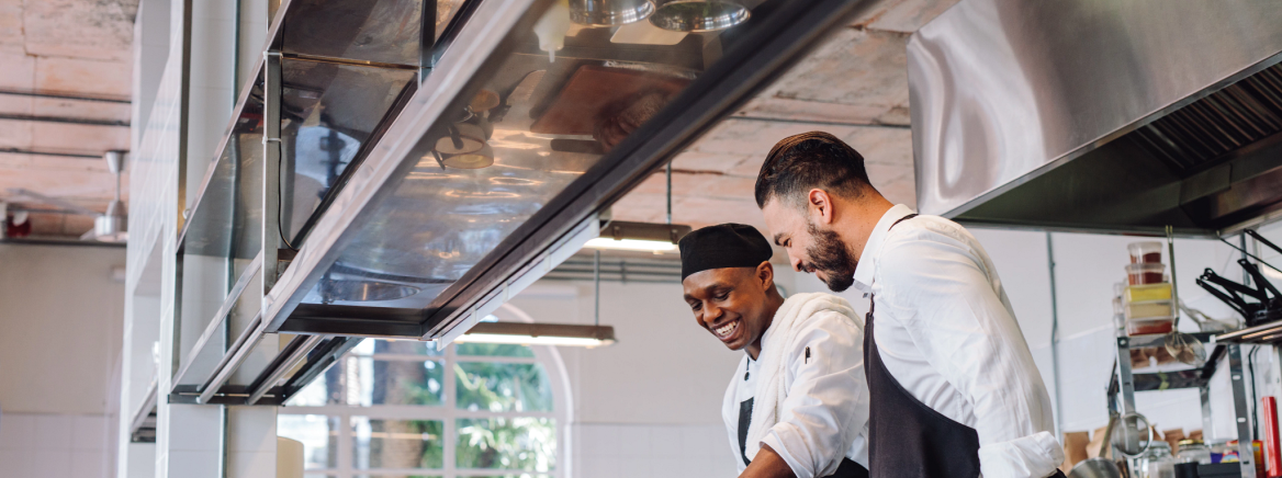 Two chefs preparing food in the kitchen.