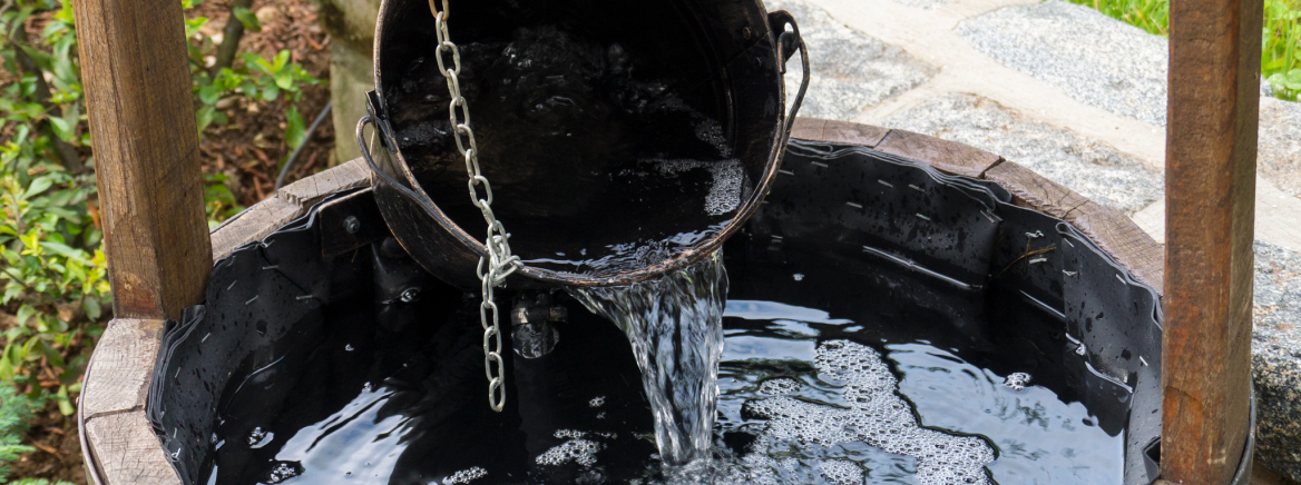 bucket pouring water into well