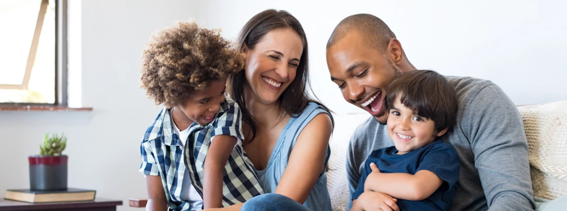 A happy family laughing on the sofa.