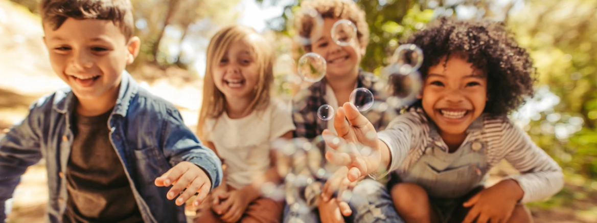 A group of children laughing while blowing bubbles