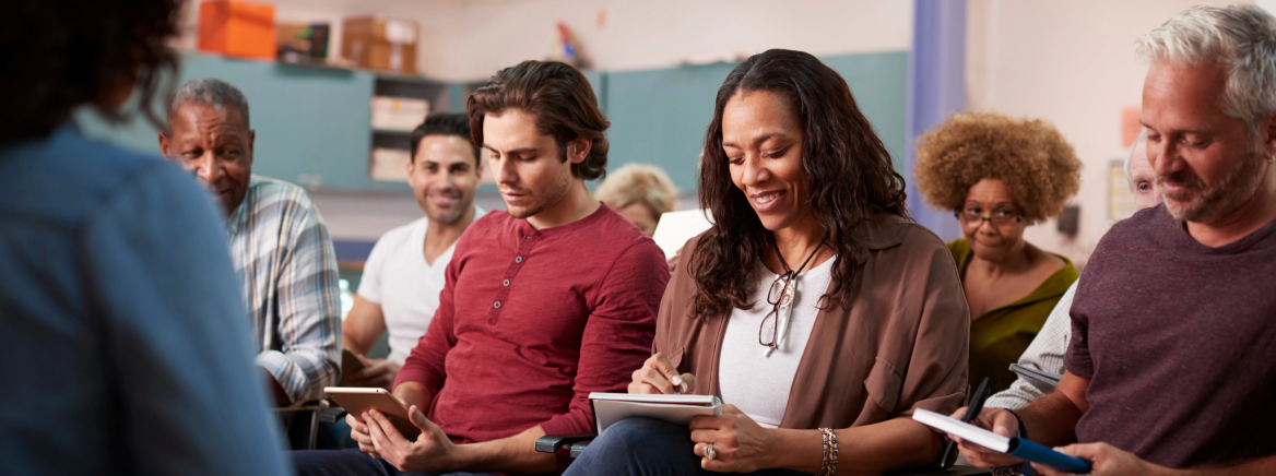 Group Making Notes Whilst Attending Neighborhood Meeting In Community Center
