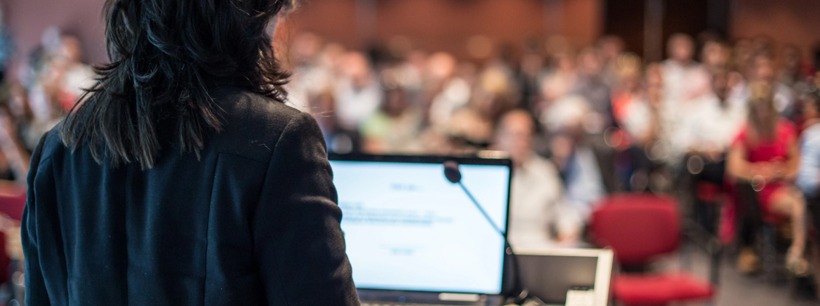 A woman presenting to a full auditorium