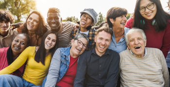 Group of multigenerational people smiling in front of camera - Multiracial friends od different ages having fun together - Main focus on caucasian senior faces