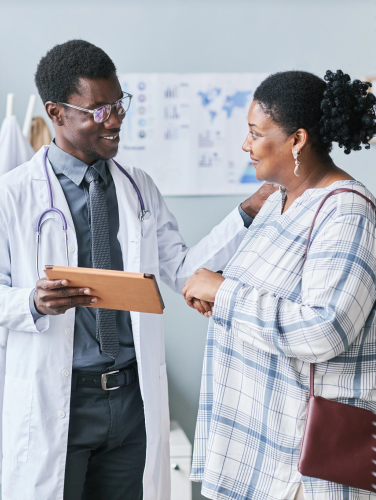 Waist up portrait of young African American doctor consulting female patient using digital tablet in clinic setting