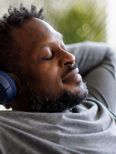 Young man enjoying music over headphones while relaxing on the sofa at home