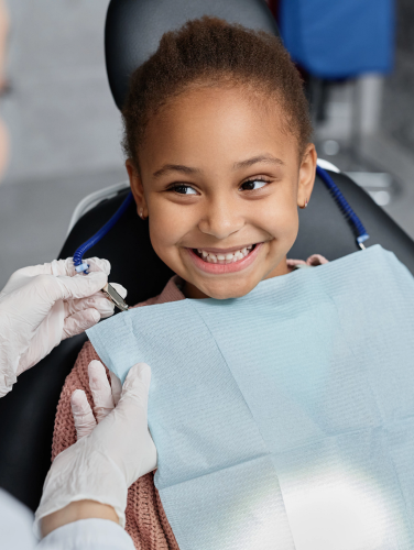 A female child in a dental child while a female dentist conducts a dentist appointment.