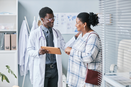Waist up portrait of young African American doctor consulting female patient using digital tablet in clinic setting