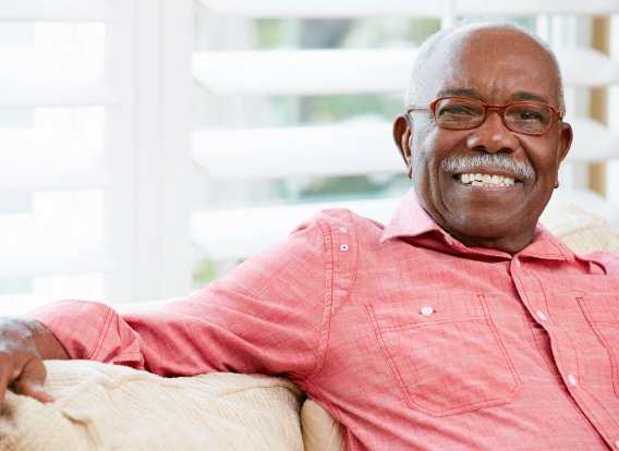 Senior-Man-Sitting-Couch Senior Man Sitting on Couch Smiling