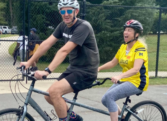 Accessible bicycle Two individuals riding an accessible bicycle.