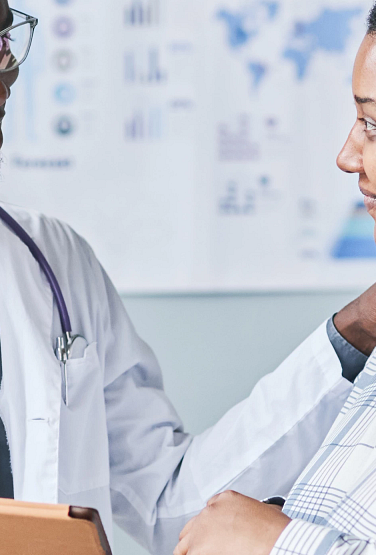 Waist up portrait of young African American doctor consulting female patient using digital tablet in clinic setting