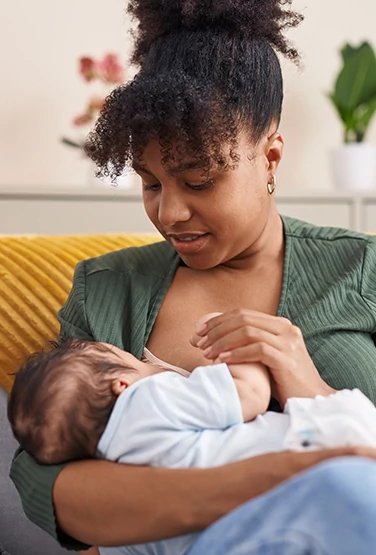 Mother and son sitting on sofa breastfeeding at home